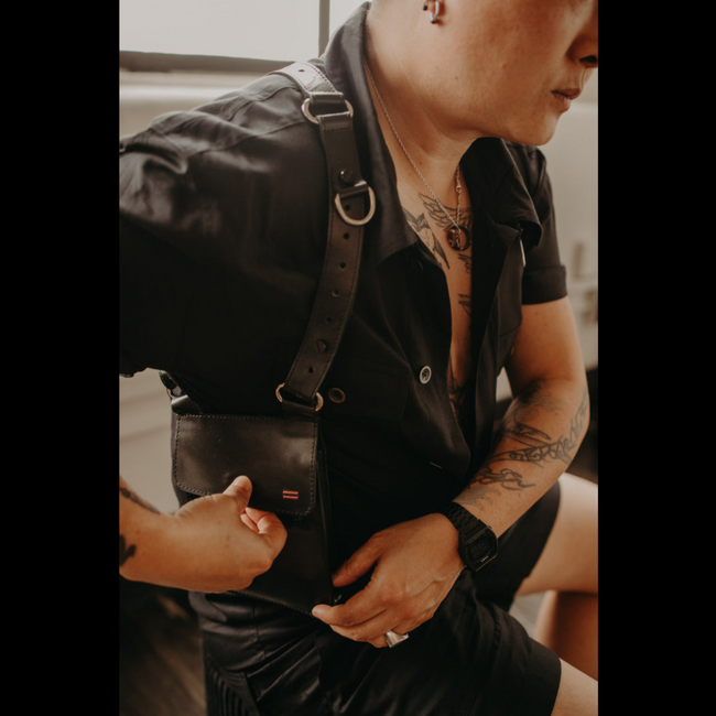 NiK Kacy wearing their Holster Harness 2.0 over casual attire, demonstrating its hands-free functionality and modern unisex styling.